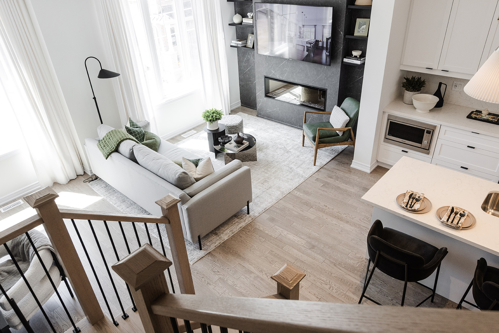 Modern living room with a light gray sofa, green accent pillows, a black floor lamp, a green armchair, and a sleek fireplace, showcasing a stylish interior design suitable for home marketing campaigns.
