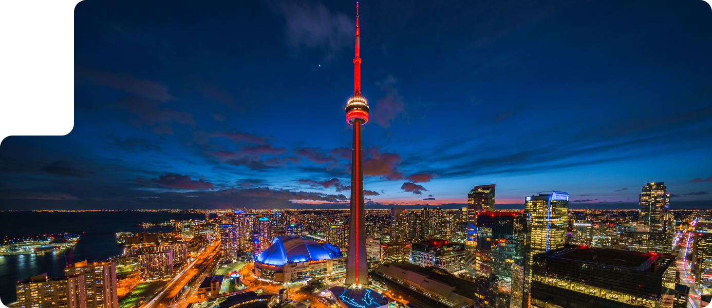 Aerial view of Toronto skyline at night featuring the CN Tower illuminated in red, showcasing vibrant city lights and urban landscape, relevant to ROC Media's drone services for real estate and promotional videography.