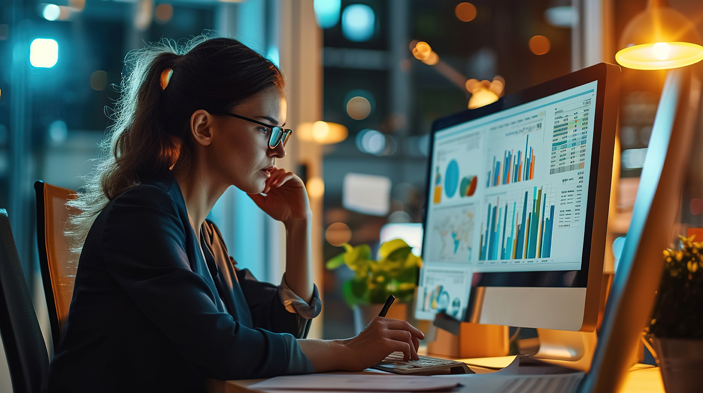 Woman analyzing data on computer screen with graphs and charts, illustrating strategic media management and campaign optimization for ROC Media's marketing services.