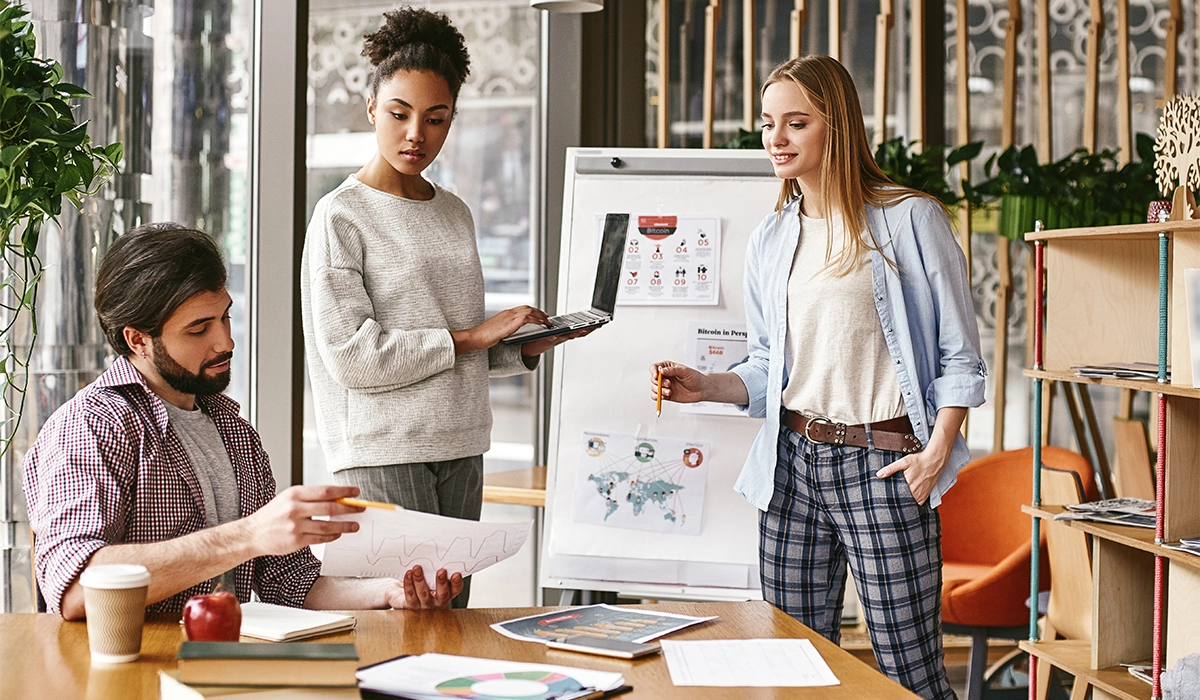 Team collaborating on marketing strategy in a modern office, reviewing documents and discussing plans, emphasizing in-house vs. agency support for effective marketing.