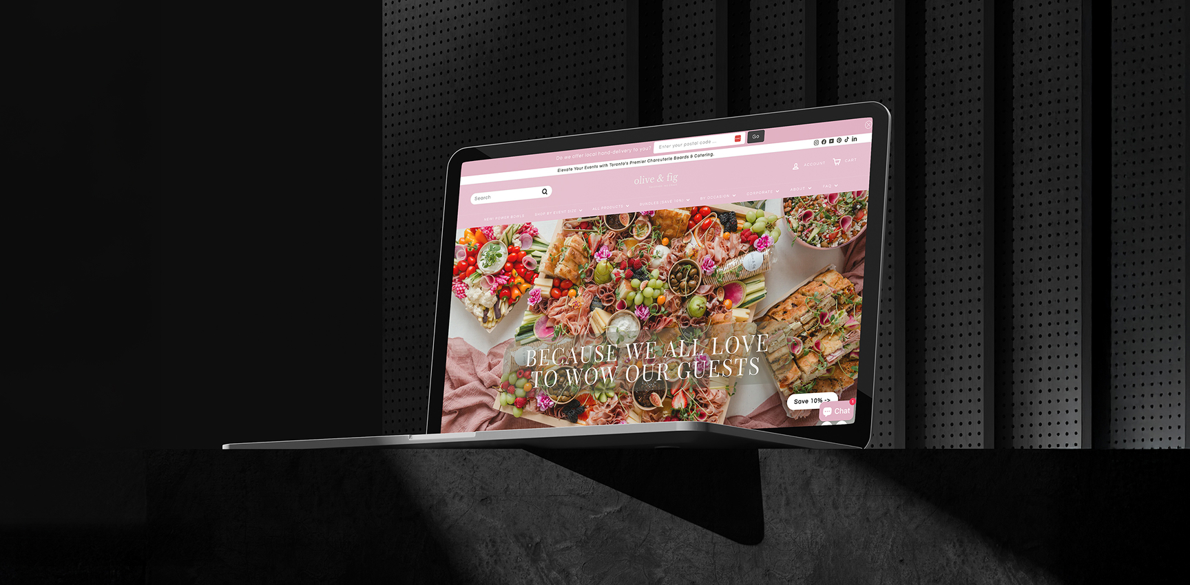 Laptop displaying the Olive & Fig website featuring colorful food platters and the text "BECAUSE WE ALL LOVE TO WOW OUR GUESTS," illustrating the brand's catering offerings and enhanced online shopping experience.