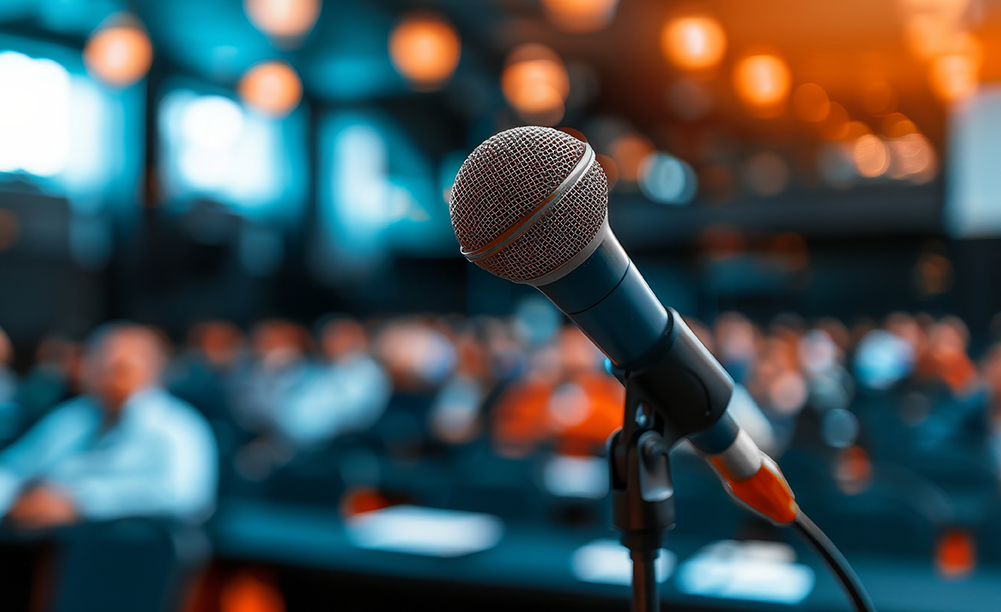 Microphone in focus at a conference setting, representing public relations and media outreach services.