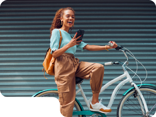 Woman smiling and using smartphone while sitting on a bicycle, showcasing a vibrant lifestyle and engagement in digital activities, reflecting ROC Media's focus on innovative marketing solutions.