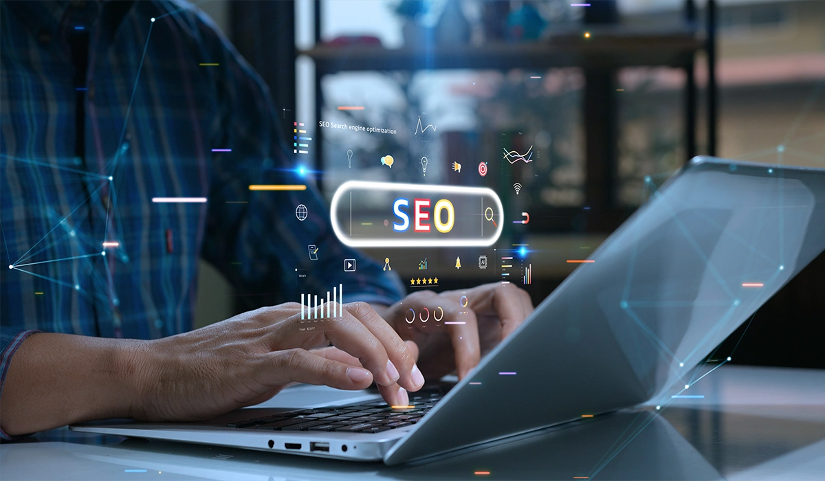 Hands typing on a laptop with a digital overlay displaying "SEO" and various marketing icons, illustrating the importance of SEO in digital marketing strategies.