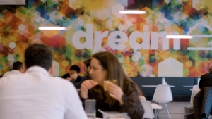 Two people engaged in conversation in a vibrant office space featuring a colorful mural with the word "dream," reflecting the innovative culture highlighted in ROC Media's video about the workplace environment at DREAM.